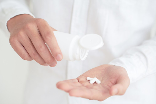 uma mão com pílulas de remédios para simbolizar estimulantes sexuais