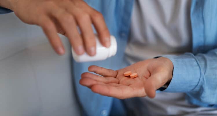 Imagem de um homem colocando uns medicamentos na mão para simbolizar o que é tadalafila e para que serve