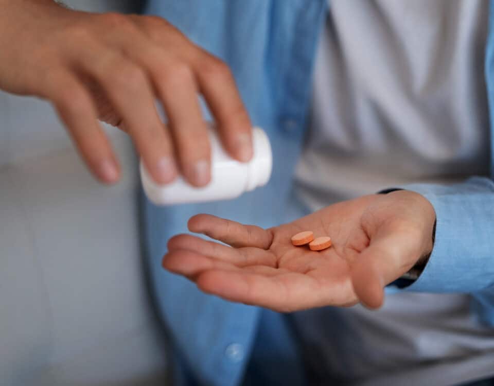 Imagem de um homem colocando uns medicamentos na mão para simbolizar o que é tadalafila e para que serve