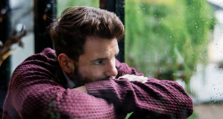 Imagem de um homem escorado na janela triste para simbolizar o que é sífilis