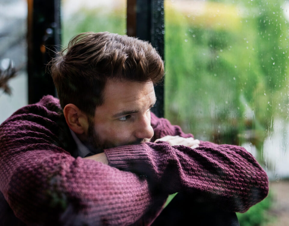 Imagem de um homem escorado na janela triste para simbolizar o que é sífilis