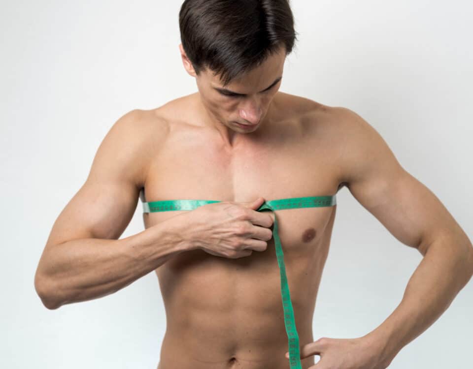 Imagem de um homem com uma fita métrica nas mamas para simbolizar a ginecomastia masculina