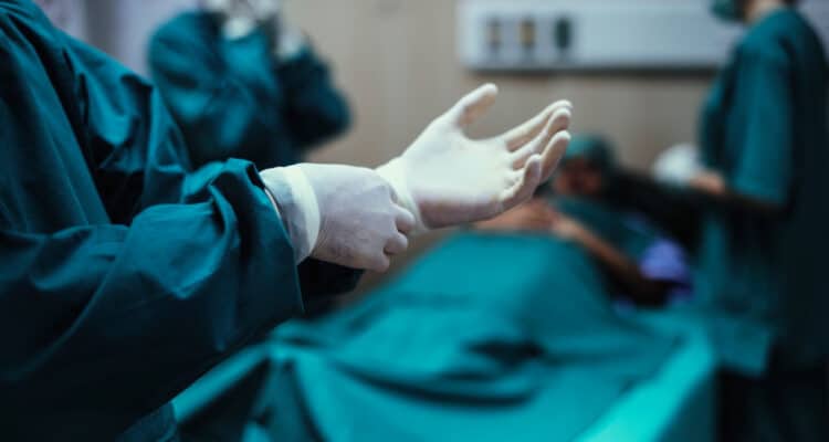 Imagem de um médico colocando as luvas em uma sala de cirurgia para simbolizar a prostatectomia radical